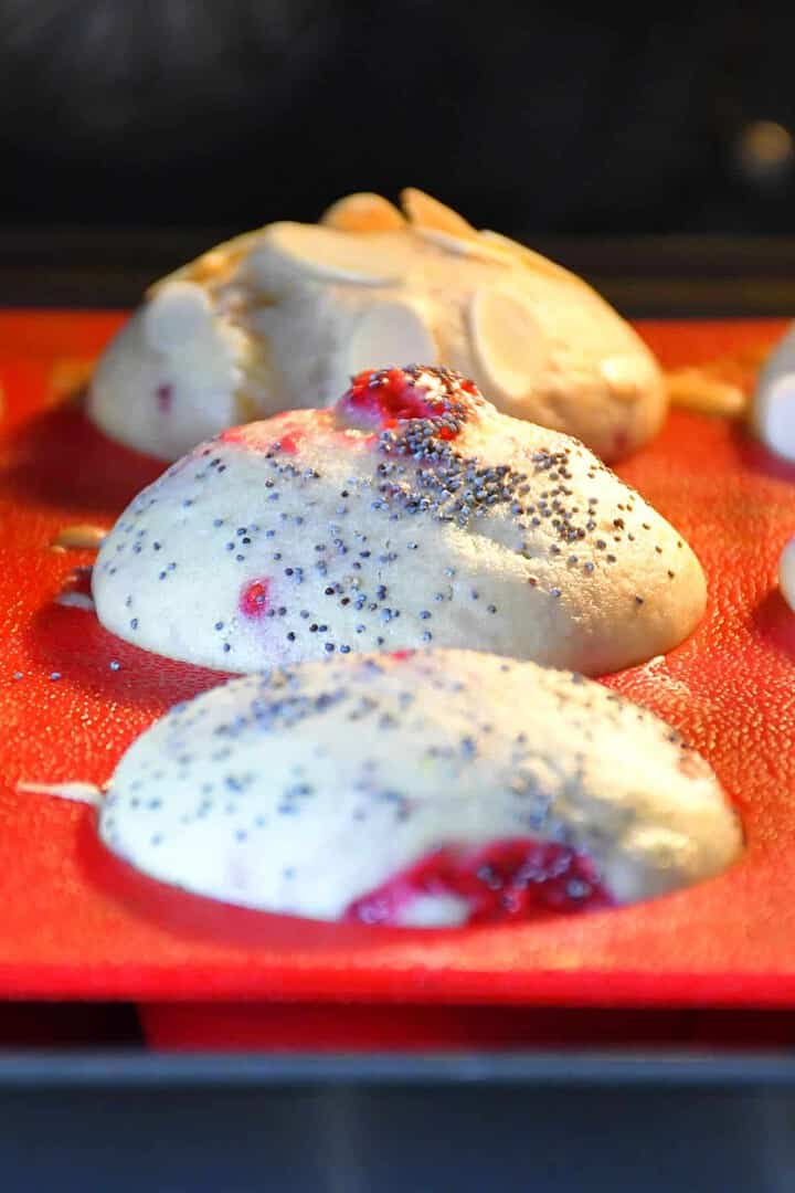 Gros plan sur de nombreuses variantes de muffins au citron et à la framboise cuits au four dans un moule en silicone rouge.