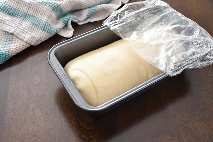 Laissez la pâte à pain blanche sans sel lever dans un moule à pain huilé recouvert d'une pellicule de plastique huilée.
