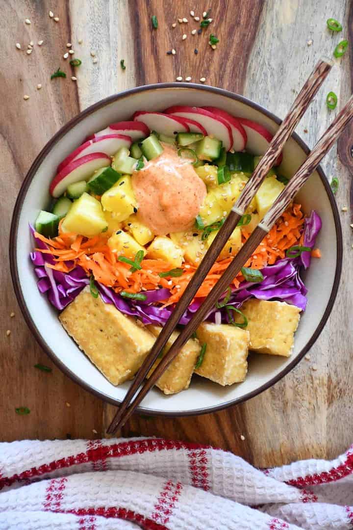 Poke bowl végétarien fait de légumes frais, de riz brun, de tofu cuit au four et de sauce paprika.