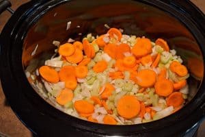 Chopped onions, carrots and celery in the bottom of a slow cooker.