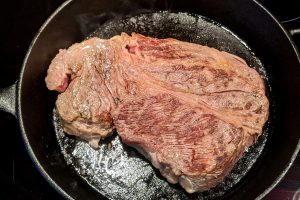 A well seared beef chuck roast in a cast iron skillet.