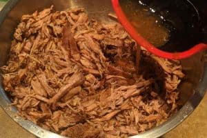 Add broth to pulled beef and mix to make it juicy.