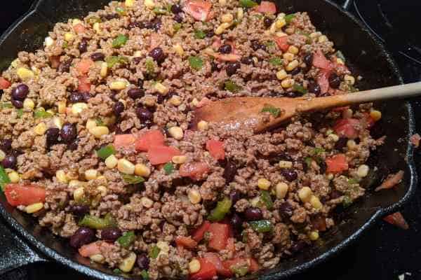 Burrito meat mix cooking in a iron pan with a lot of vegetables and a low sodium seasoning.