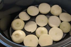A layer of sliced onions to avoid the meat sticking and burning in the bottom of the slow cooker and to add flavor.