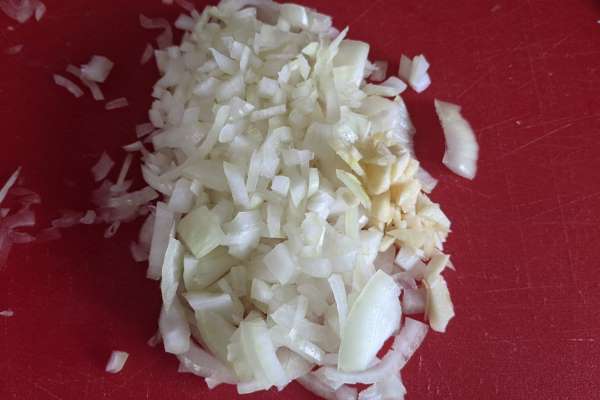 Chopped onions and garlic on a cutting board.
