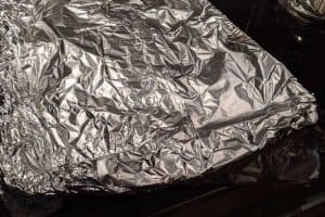 Red peppers cooling under aluminium foil to remove the skin when cooled.