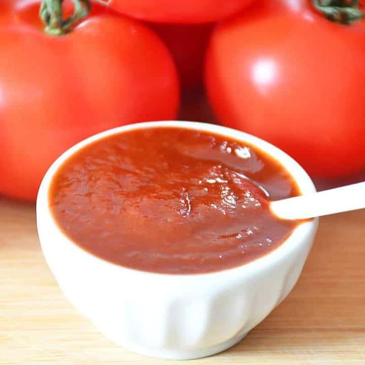 no salt simple homemade ketchup recipe presentation with tomatoes background.