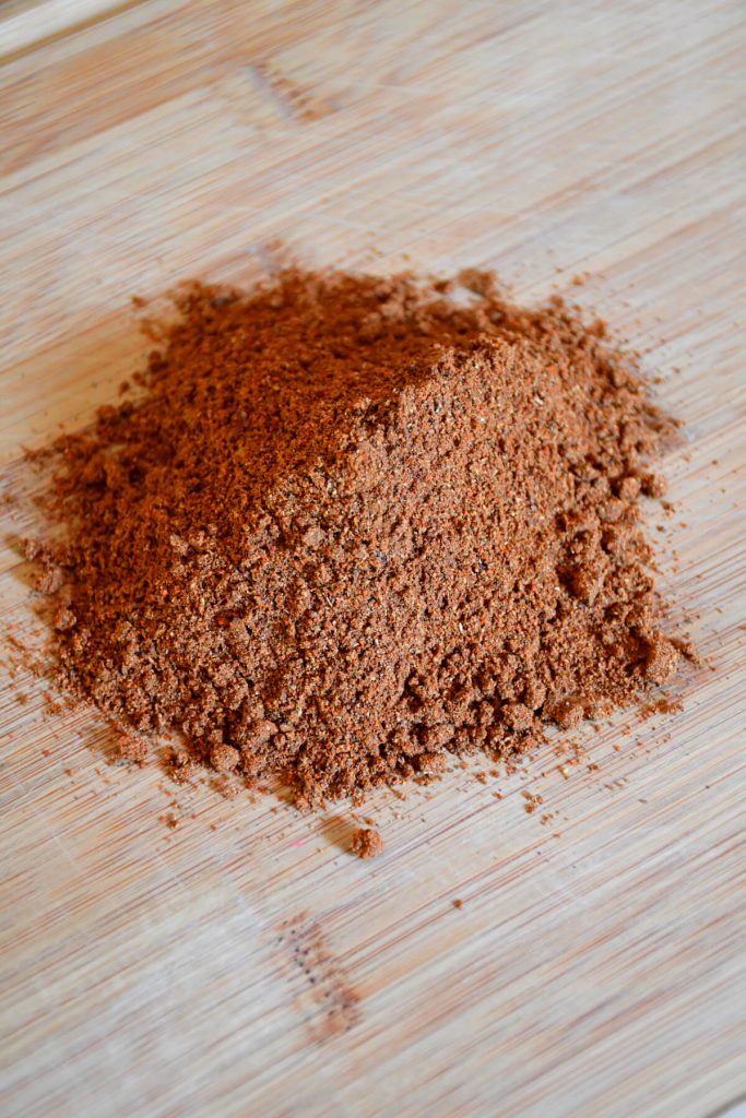 Un portrait du mélange d'épices Baharat à faible teneur en sodium présenté sur une planche de bois.