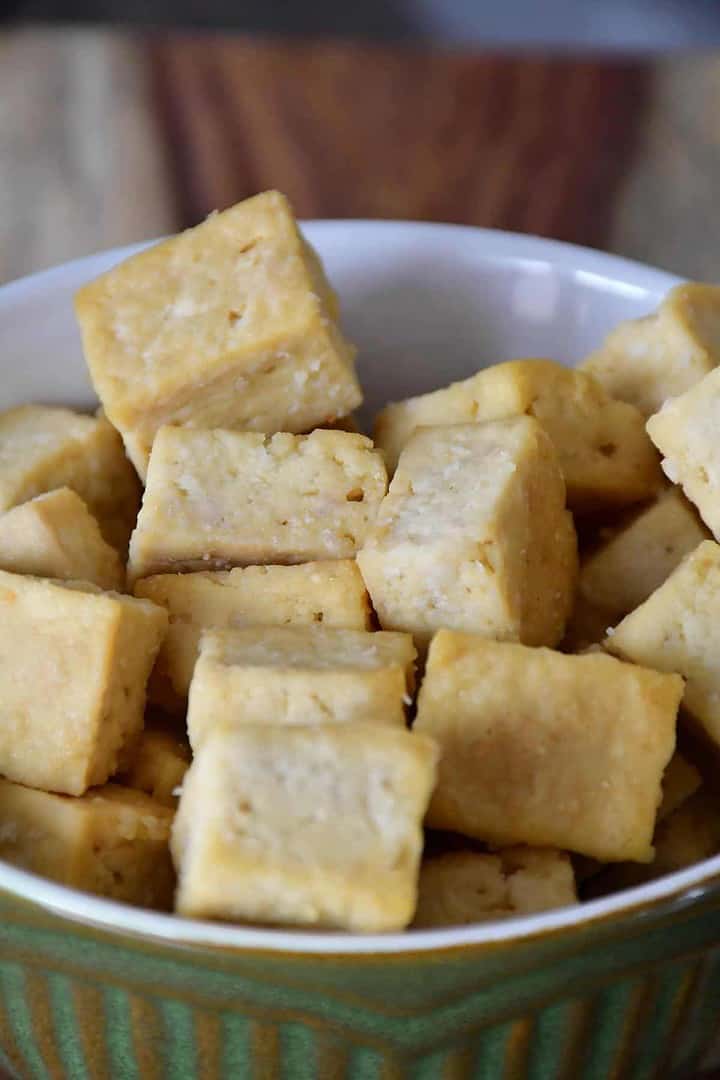 A close-up on plain baked tofu cubes in a classic green bowl.