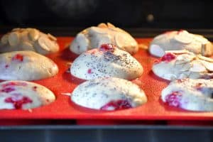 De nombreuses variantes de muffin citron framboise dans le four dans un moule à muffins en silicone rouge.