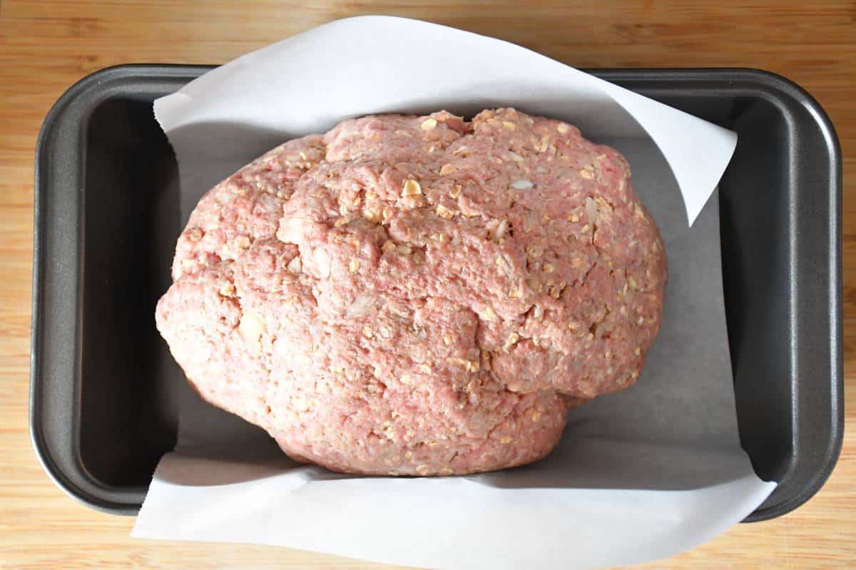 Pain de viande faible en sodium cru dans un moule à pain de viande recouvert d'une pièce de papier parchemin.
