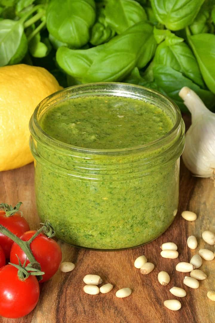Low sodium pesto presented with cherry tomatoes, garlic, basil leaves, and pine nuts.